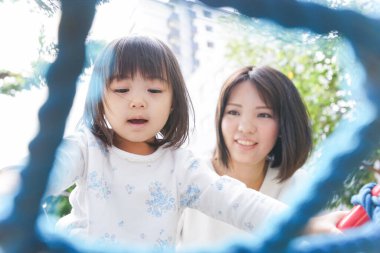 Anne ve çocuk parkta birlikte oynuyorlar.