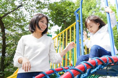 Anne ve çocuk parkta birlikte oynuyorlar.