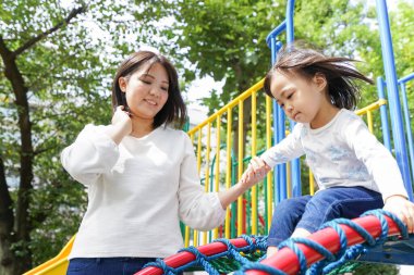 Anne ve çocuk parkta birlikte oynuyorlar.