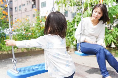 Anne ve çocuk parkta birlikte oynuyorlar.