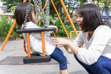 Anne ve çocuk parkta birlikte oynuyorlar.