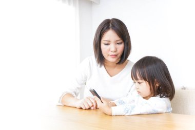 Anne ve çocuk akıllı telefonu birlikte kullanıyorlar.