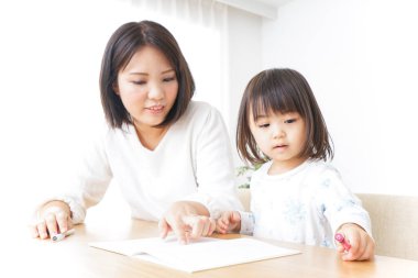 Anne ve kızı evde masada otururken ders çalışıyor.