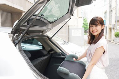 Çocuk arabası koltuğu olan genç Asyalı kadın.