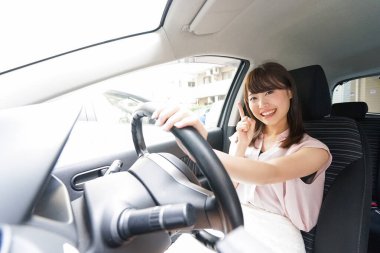 Genç Asyalı kadın sürücü bir şey gösteriyor.