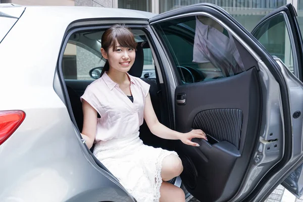 若いアジアの女性が車から出て — ストック写真