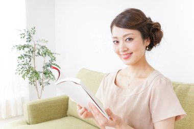 Kadın odada kitap okuyor.