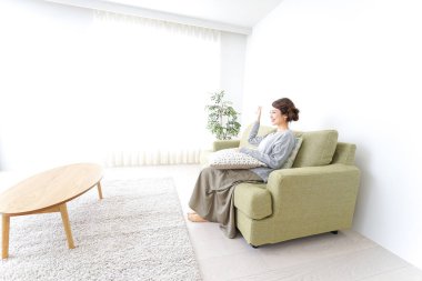 Bekar bir kadın, evinde, kanepede dinleniyor.