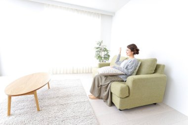 Bekar bir kadın, evinde, kanepede dinleniyor.