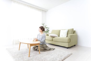 Kadın kahve içiyor ve evde dinleniyor.