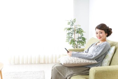 Akıllı telefon kullanan ve koltukta oturan bir kadın.