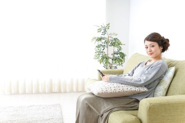 Akıllı telefon kullanan ve koltukta oturan bir kadın.