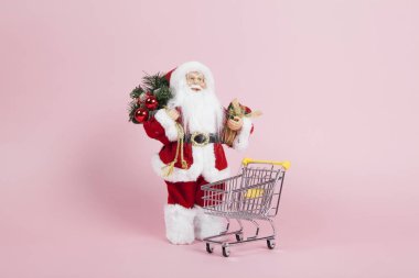 Alışveriş arabası yakınında Santa Claus pembe arka plan