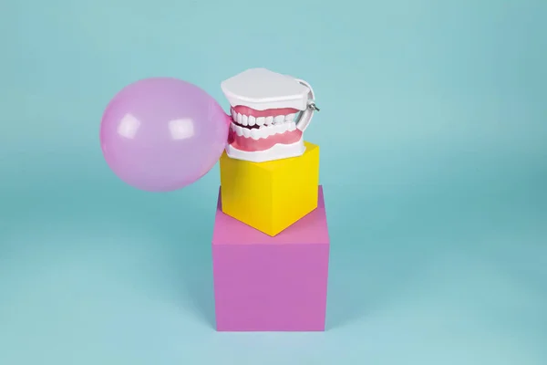 色のついた立方体にガムボールを保持して歯を磨く方法を学ぶ解剖学的プラスチック歯モデル ユーモアとポップの雰囲気をオフビート 最小限の色静物写真 — ストック写真