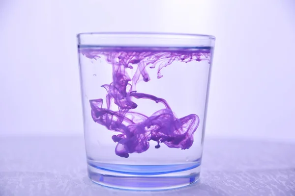 Vidro Com Água Sobre Fundo Branco Com Tinta Roxa — Fotografia de Stock