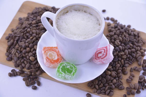 Kaffebønner og slik på en hvid underkop - Stock-foto