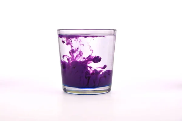 Vidrio Con Agua Sobre Fondo Blanco Con Pintura Púrpura Imagen De Stock