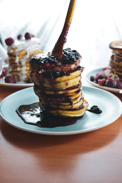 Pancake with dripping jam on a blue plate with raspberries — Stock Photo, Image