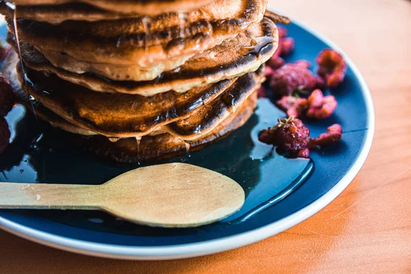 Pannkaka med droppande honung på en blå tallrik med hallon — Stockfoto