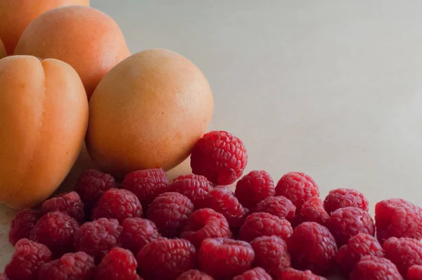 Frische Himbeeren und reife Aprikosen auf hölzerner Texturoberfläche. Nahaufnahme und Kopierraum — Stockfoto