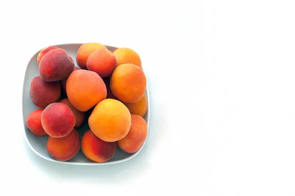 Geïsoleerde verse sappige perziken vruchten en rijpe abrikozen geïsoleerd op witte plaat. Zomer fruit concept. Close-up. Copyspace voor uw tekst — Stockfoto