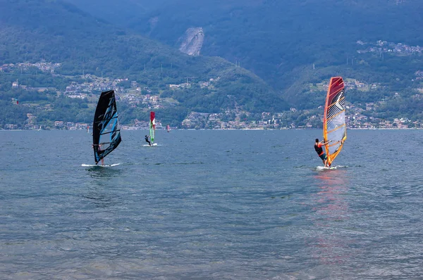 Lago de Como, Italia - 21 de julio de 2019. Deportes acuáticos: grupo de tres windsurfistas montados en un soleado día de verano cerca del Colico, ciudad de Italia. Montañas Alp en el fondo. Windsurf en el lago Ven, competitio — Foto de Stock