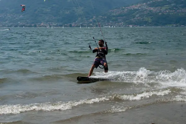 Lago de Como, Italia - 21 de julio de 2019. Deportes acuáticos: kitesurfista en un soleado día de verano cerca del Colico, ciudad en Italia. Montañas Alp en el fondo. Kiteboarding, deporte extremo . — Foto de Stock