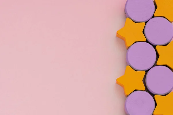 Top uitzicht op veelkleurige kids speelgoed op licht roze papier achtergrond. Houten oranje sterren, Lila cirkels aan de rechterkant. Kopieer ruimte voor tekst, close-up. — Stockfoto