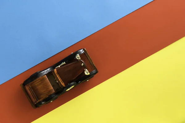 Retro vintage auto op veelkleurige papieren achtergrond. Vakantie, levering, reisconcept. Bovenaanzicht, vlak. Rood blauwe gele stippen. Diagonale richting. — Stockfoto