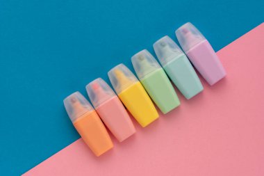 Renkli mavi arkaplanda fosforlu kalemler var. İşaretleyici koleksiyonu farklı renkte. Düz yerde, üst tarafta. Okula dönmek, eğitim kavramı..