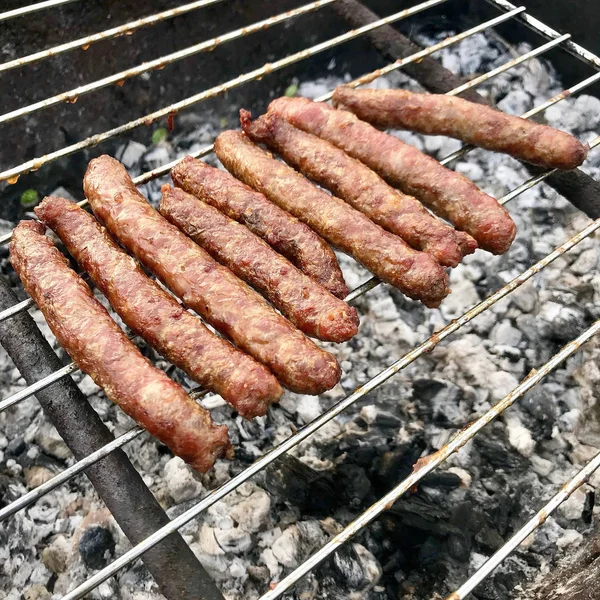 Churrasco com salsichas bávaras ardentes na grelha no jardim ao ar livre — Fotografia de Stock