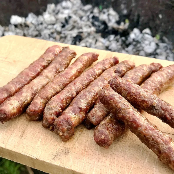Churrasco com salsichas bávaras ardentes na grelha no jardim ao ar livre — Fotografia de Stock