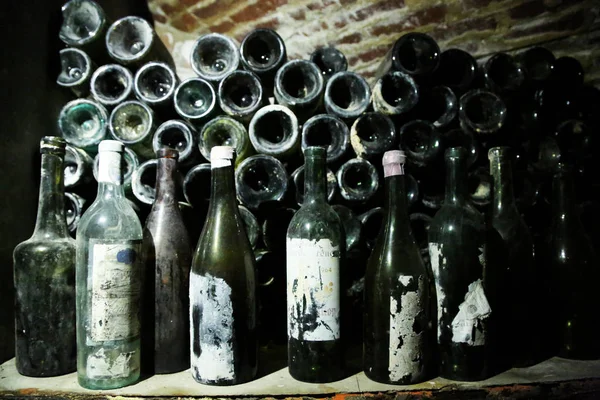 Garrafas muito antigas de vinho jaz na adega escura retro — Fotografia de Stock