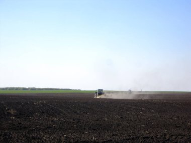 Açık kırsal alanda, kahverengi toprakta traktörle sürülmüş. Tarlada traktör, topraktan lezzetli sebzeler. Temiz mavi gökyüzünün altındaki organik tarlalar traktör için doğal topraktır..