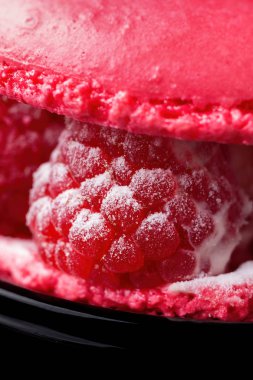 Fransızca macaroons zarif kırmızı bir arka plan gradyan ile ahududu meyveleri ile pasta. Fransız şekerlemeler hassas bir geleneksel tatlı.