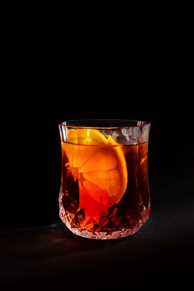Red drink in a crystal glass. Photo of a drink on a black background.