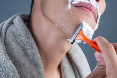 Gri bir arka planda tıraşlanmış yakışıklı bir adam..