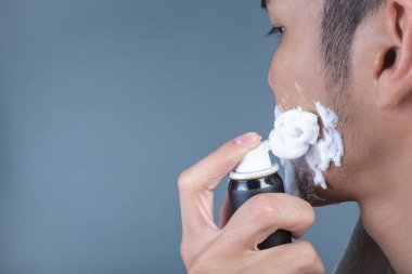 Gri bir arka planda tıraşlanmış yakışıklı bir adam..