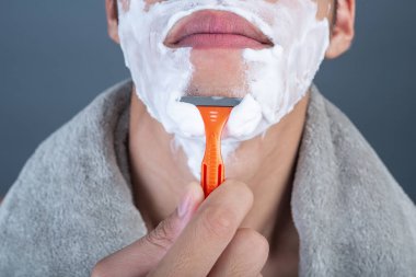 Gri bir arka planda tıraşlanmış yakışıklı bir adam..