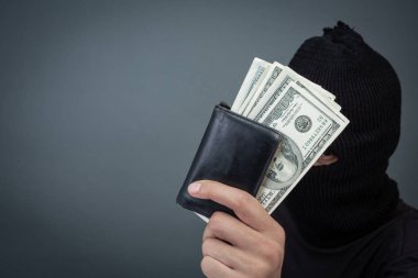Black criminals wear a head yarn, hold a dollar card on a gray background.