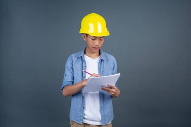 Gri arka planda beyaz kağıt tutan inşaat gençleri