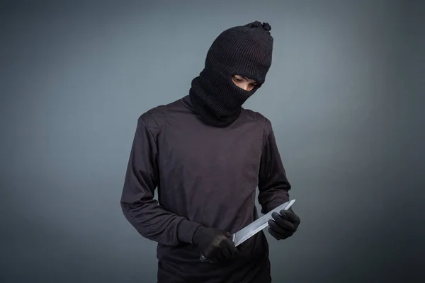 Criminals wear black mask and hold dark on gray background.