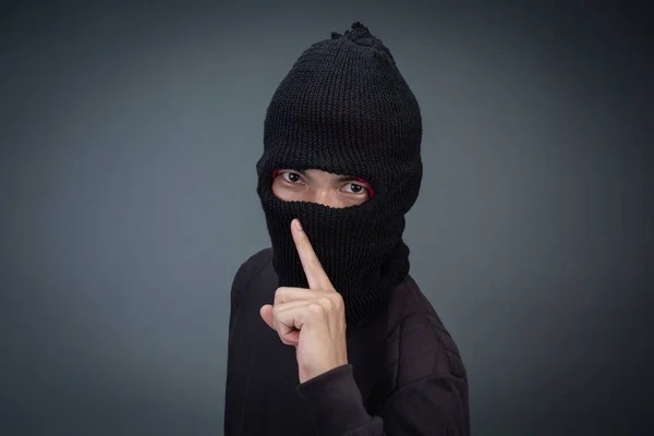 Criminals wear a mask in black on a gray background.