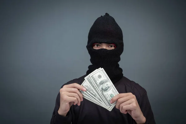 Black criminals wear a head yarn, hold a dollar card on a gray background.