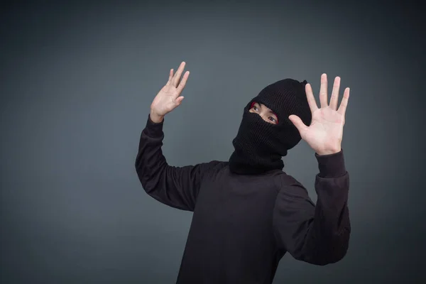 Criminals wear a mask in black on a gray background.
