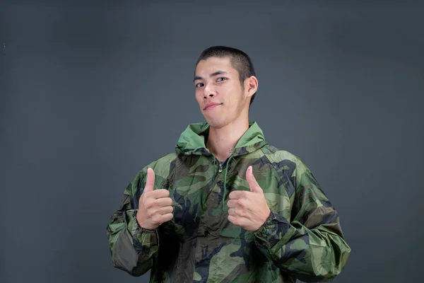 Young Man Wears Camouflage Raincoat Shows Different Gestures Gray Background — Stockfoto
