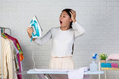 Ütüyü merak eden genç ev kadınları. Beyaz tuğlalı arka planda.