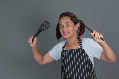 Elinde mutfak gereçleri olan yaşlı bir aşçı..