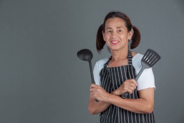 Elinde mutfak gereçleri olan yaşlı bir aşçı..