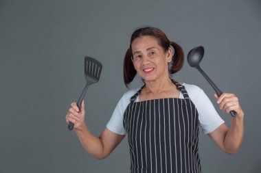 Elinde mutfak gereçleri olan yaşlı bir aşçı..